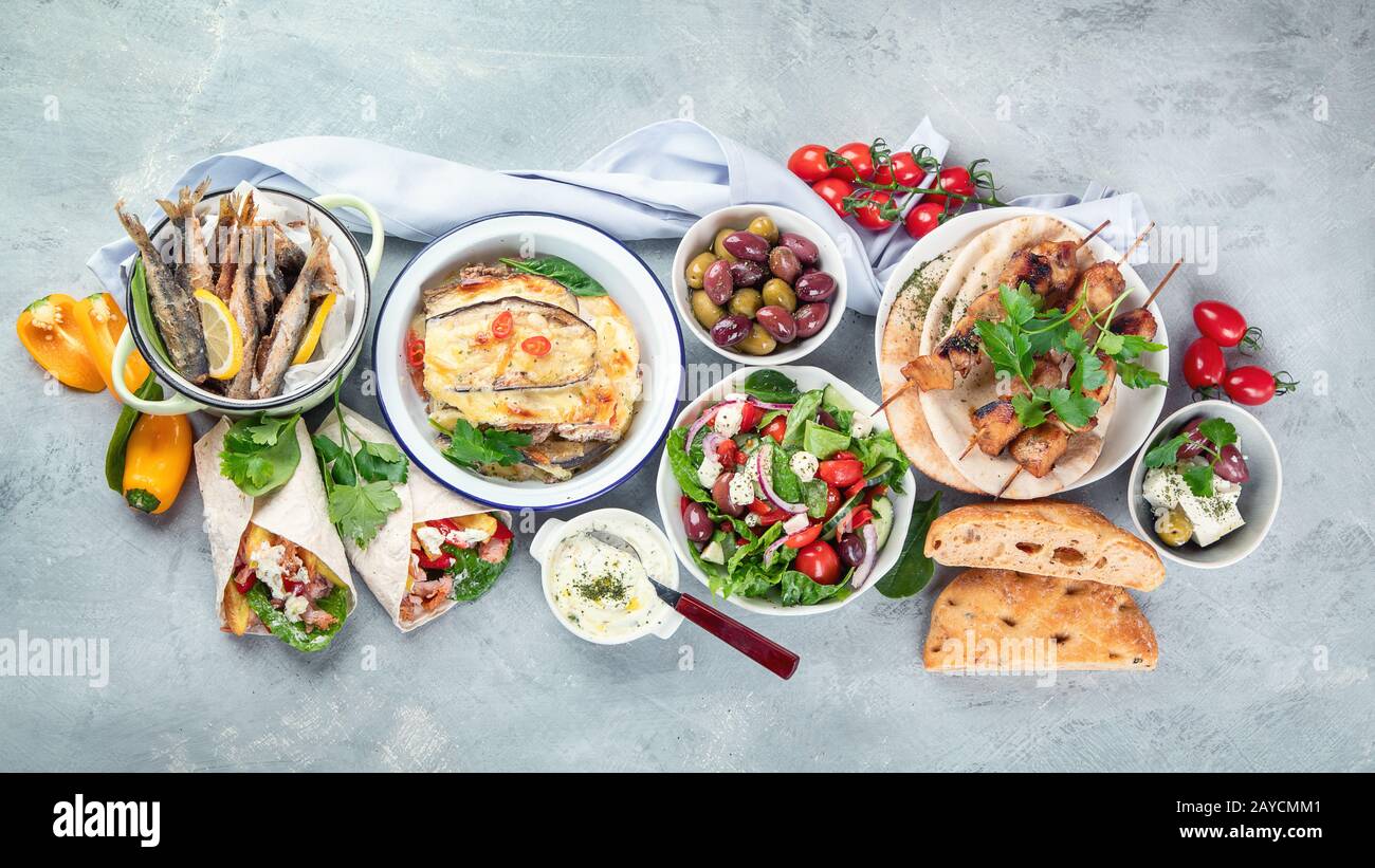 Greek food on grey background. Moussaka, gyros,souvlaki, pita, salad, olives and vegetables