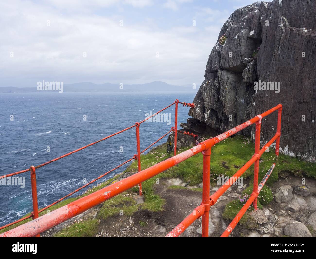 Red railing at a cliff at sheeps head lighthouse Stock Photo