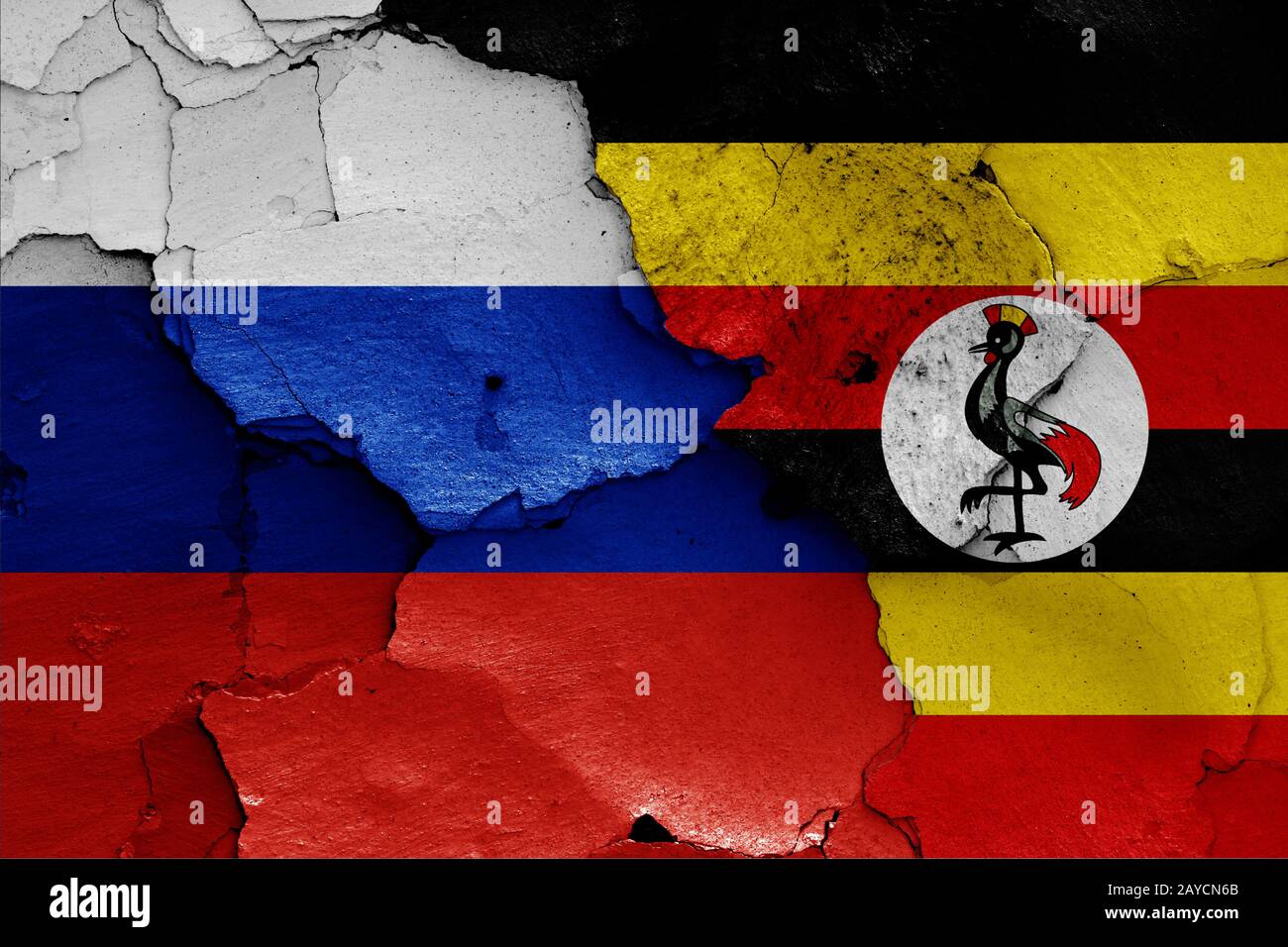 flags of Russia and Uganda painted on cracked wall Stock Photo
