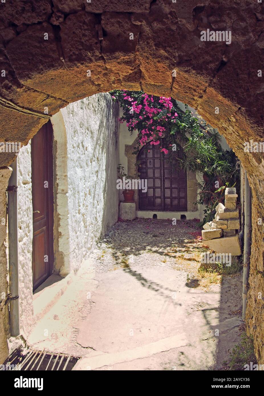 an ancient sunlit alleyway in rhodes town under a stone arch with ...