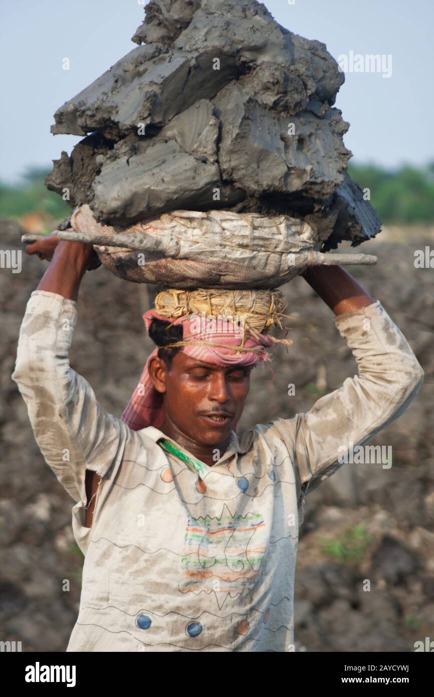 A day labourer carries a basket of soil on his head. Khulna, Bangladesh. Stock Photo