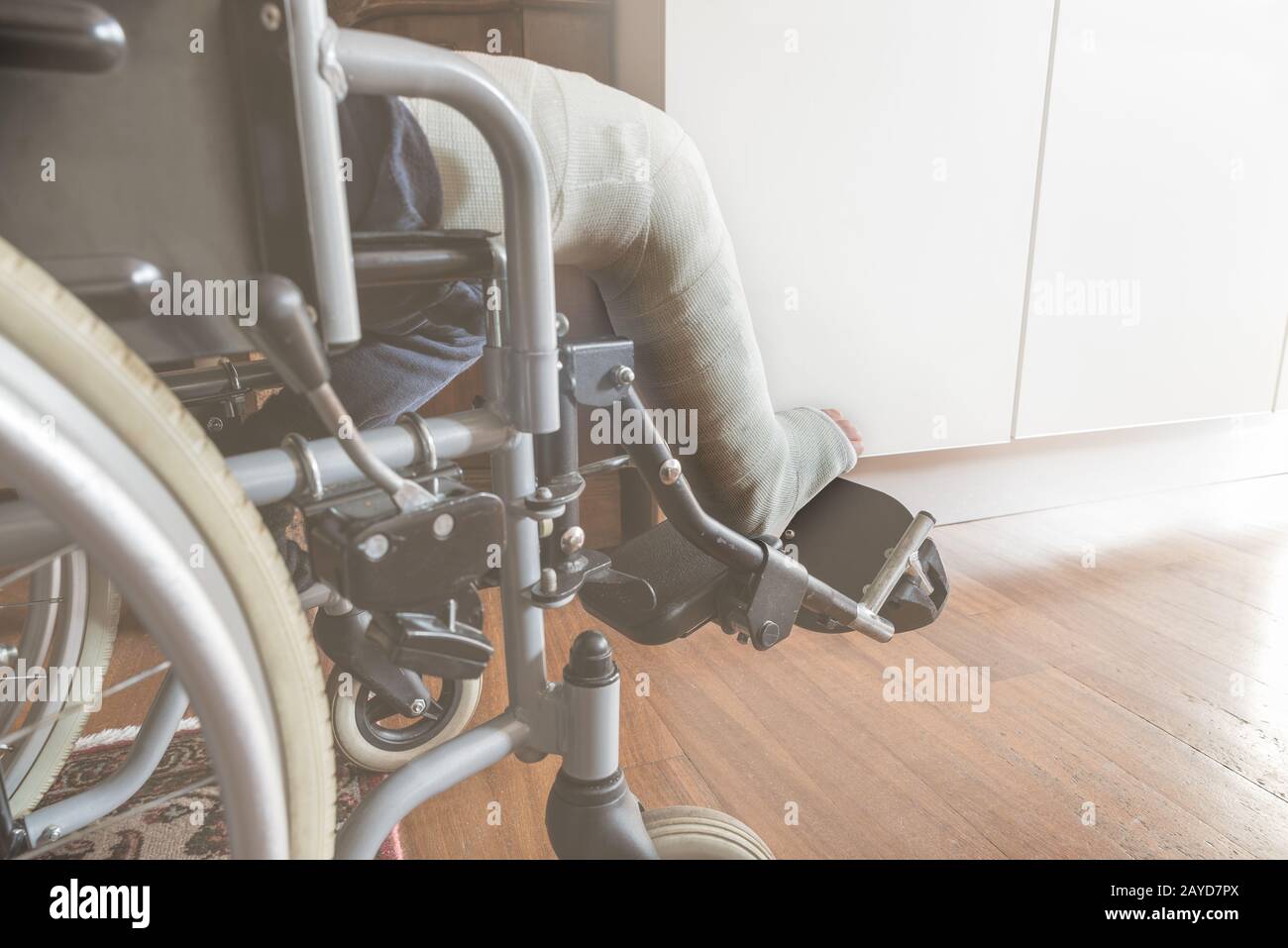 Leg in plaster of a child in a wheelchair. Concept of health, accident, medical. Selective focus on the foot, side view. Unrecognizable person Stock Photo