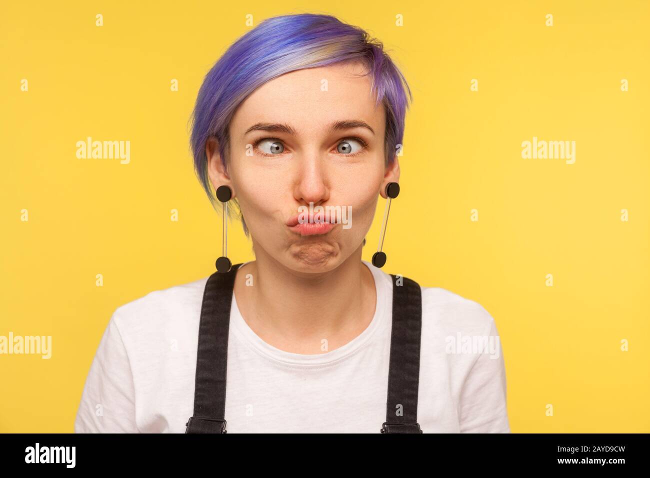 Portrait of comic hipster girl with violet short hair looking cross eyed, making silly awkward face expression, having fun and playing fool. isolated Stock Photo