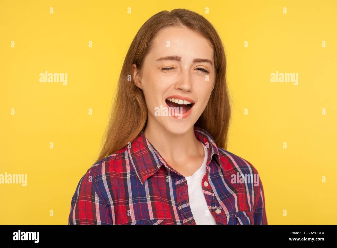 Portrait of cheerful optimistic ginger girl in checkered shirt winking