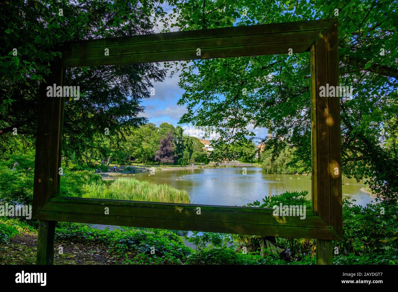 View through large hollow picture frame of pond, trees, ducks and people at Leases Park in Newcastle, England Stock Photo