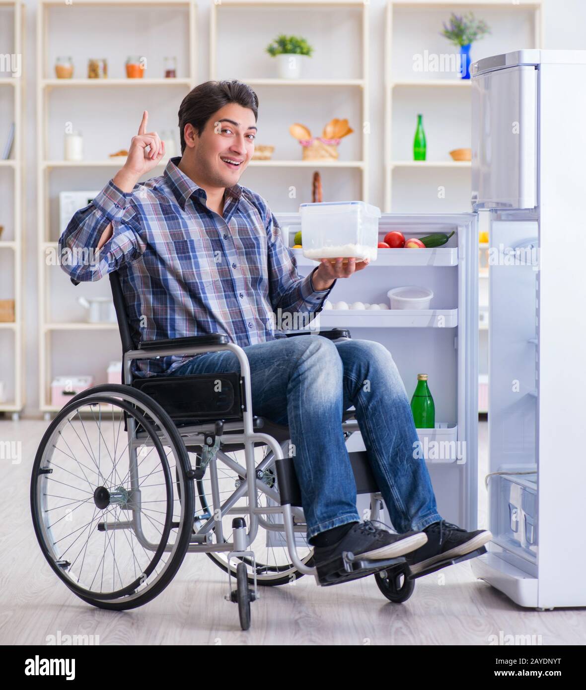 Young disabled injured man opening the fridge door Stock Photo