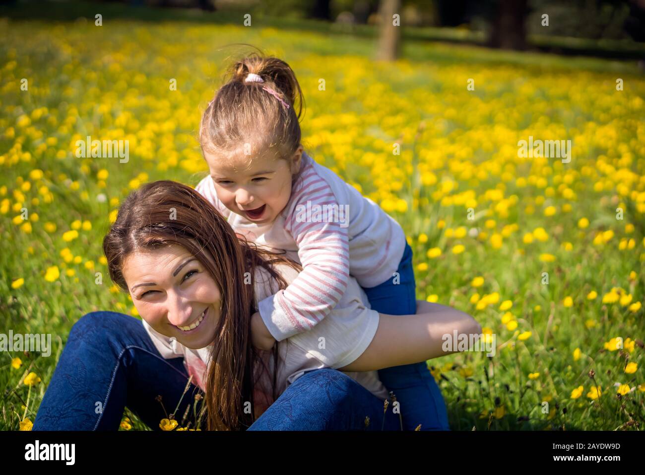 Young girl and her mom playing on meadow, family time, summer day, blurred background Stock Photo