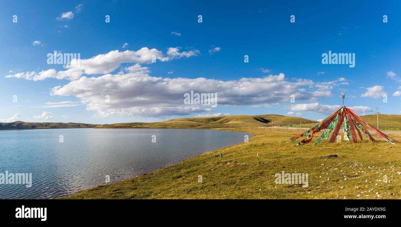 plateau sacred lake and bright flapping prayer flags Stock Photo