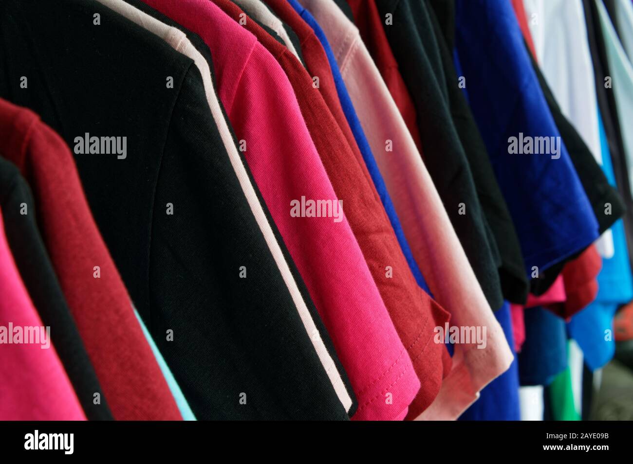 Different coloured shirts hang in a row Stock Photo