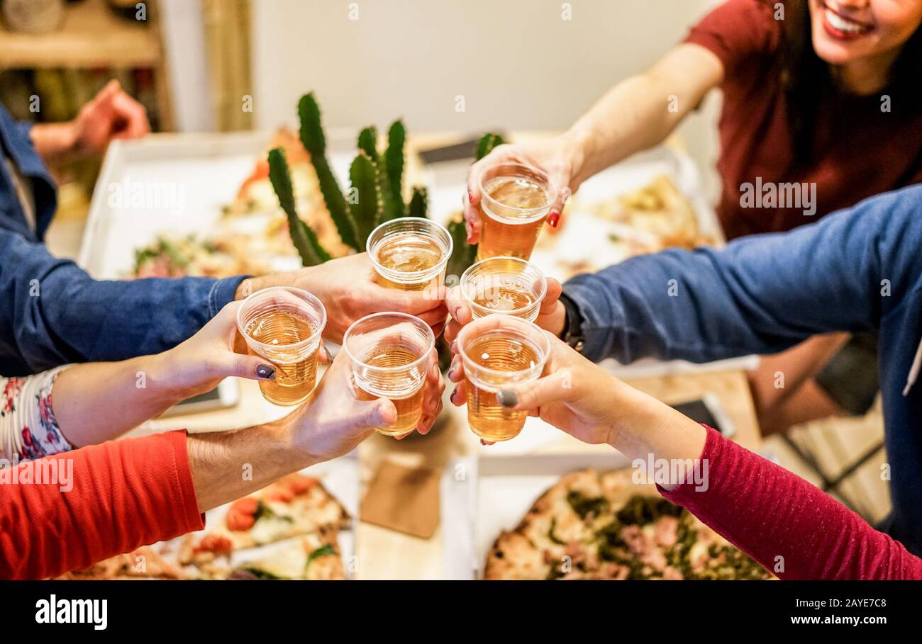 Group of happy friends cheering at home with beer - Young people having fun together eating italian pizza take away - Dinner,party and friendship conc Stock Photo