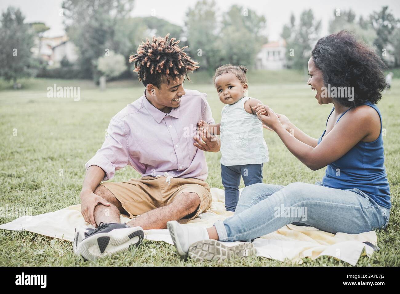 Happy black family having fun doing picnic outdoor - Parents and their daughter enjoying time together in a weekend day - Love tender moments and happ Stock Photo