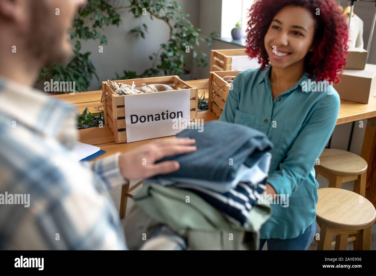 Young girl and man folding clothes for donations. Stock Photo