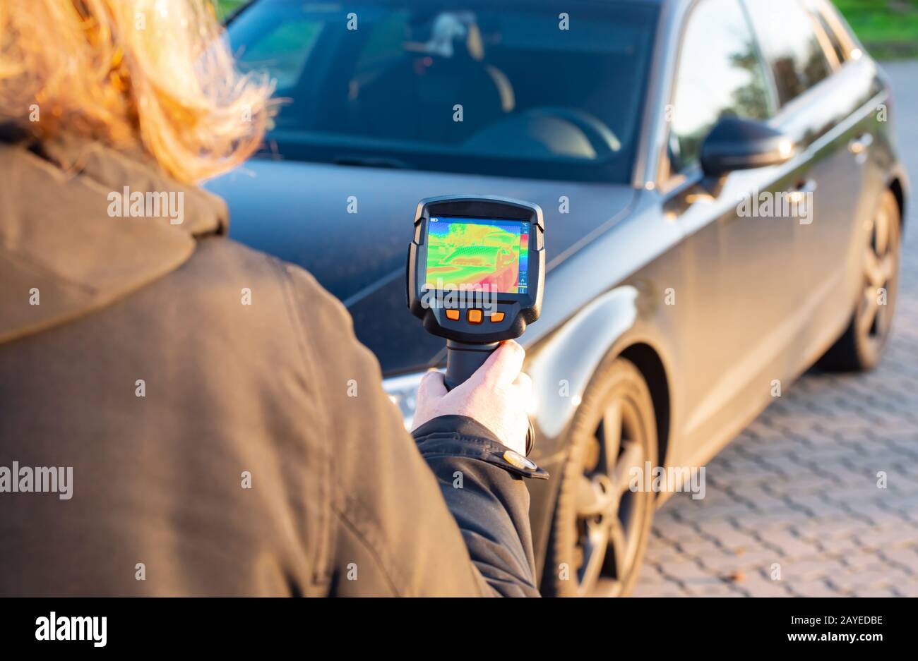 Woman shows with a thermal imager on a building to detect defects as an infrared image Stock Photo