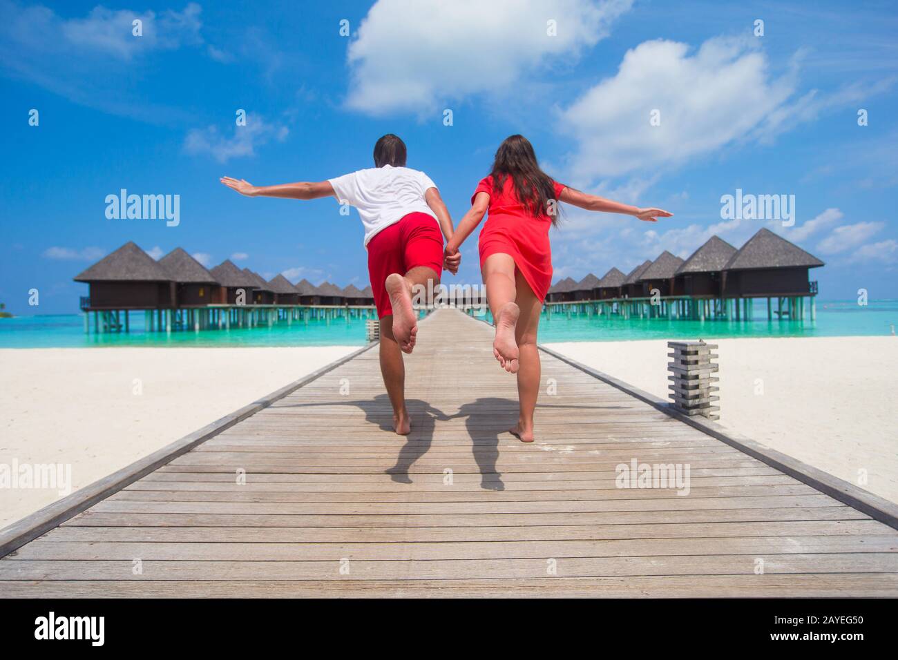 Young couple on tropical beach jetty at perfect island Stock Photo