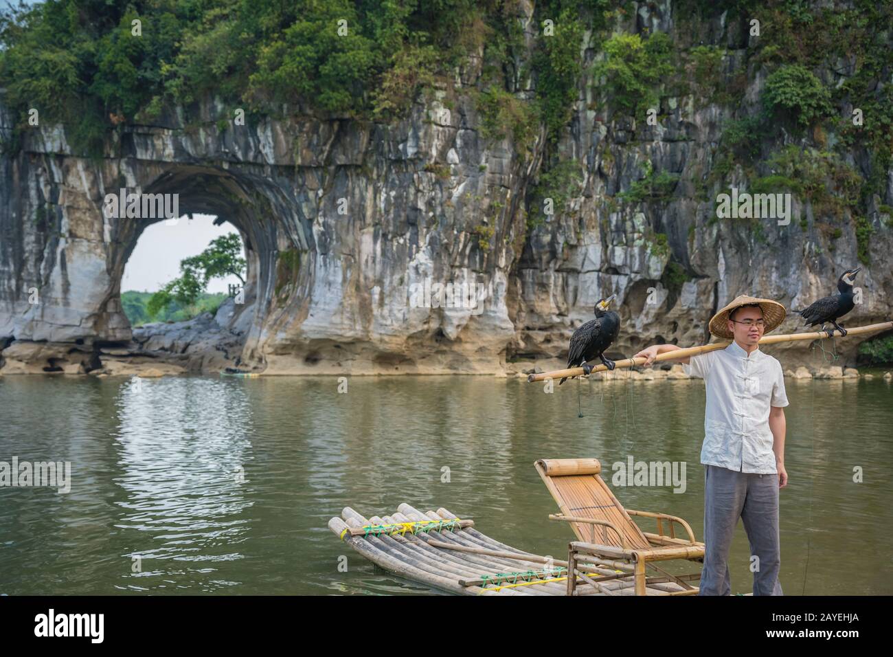 Man with cormorants in front of The Elephant Trunk Hill Arch Stock Photo