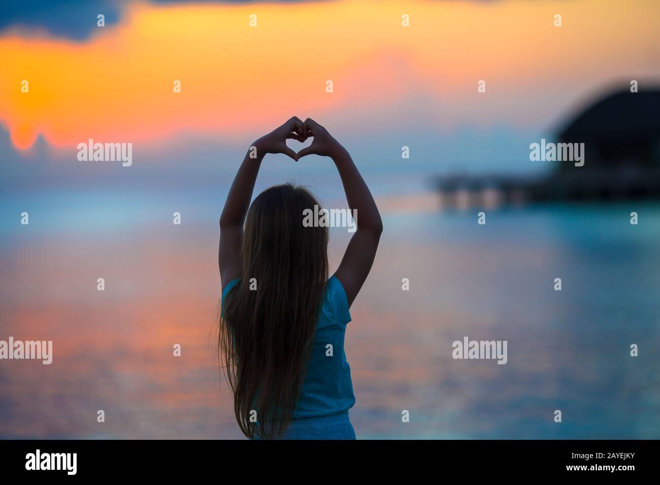 Silhouette of heart made by kids hand at sunset Stock Photo