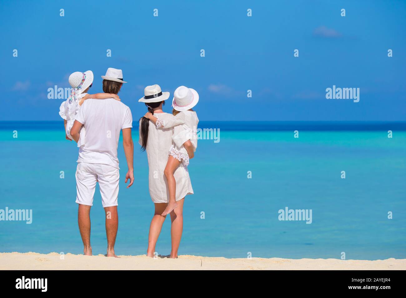 Young family of four on white beach Stock Photo