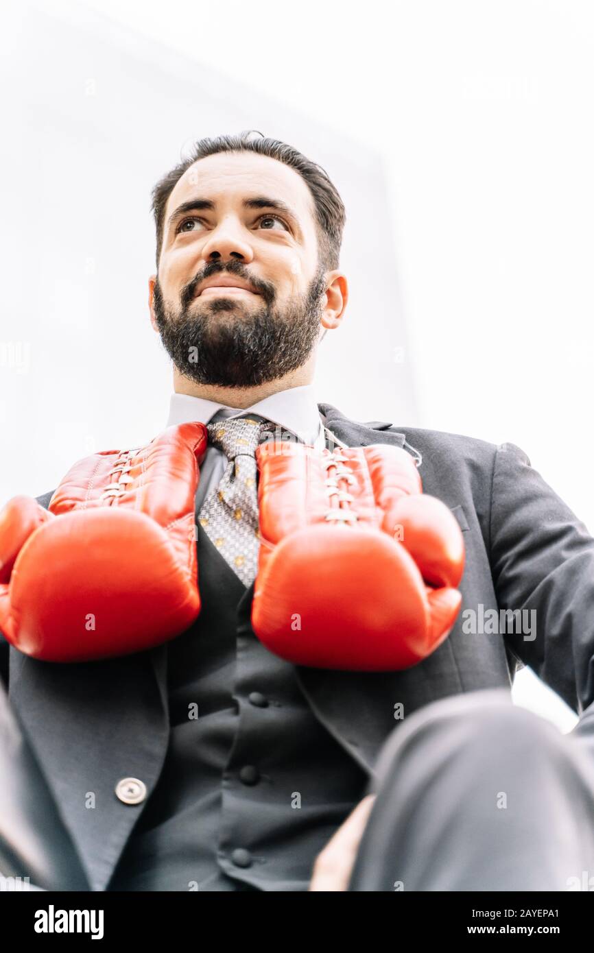 Portrait of a businessman with boxing gloves hanging from his neck in a