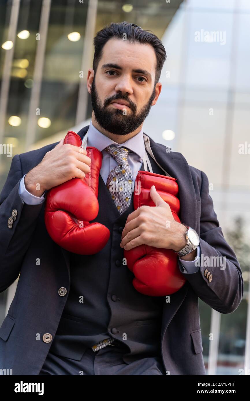 Businessman touching red boxing gloves hanging from his neck in front