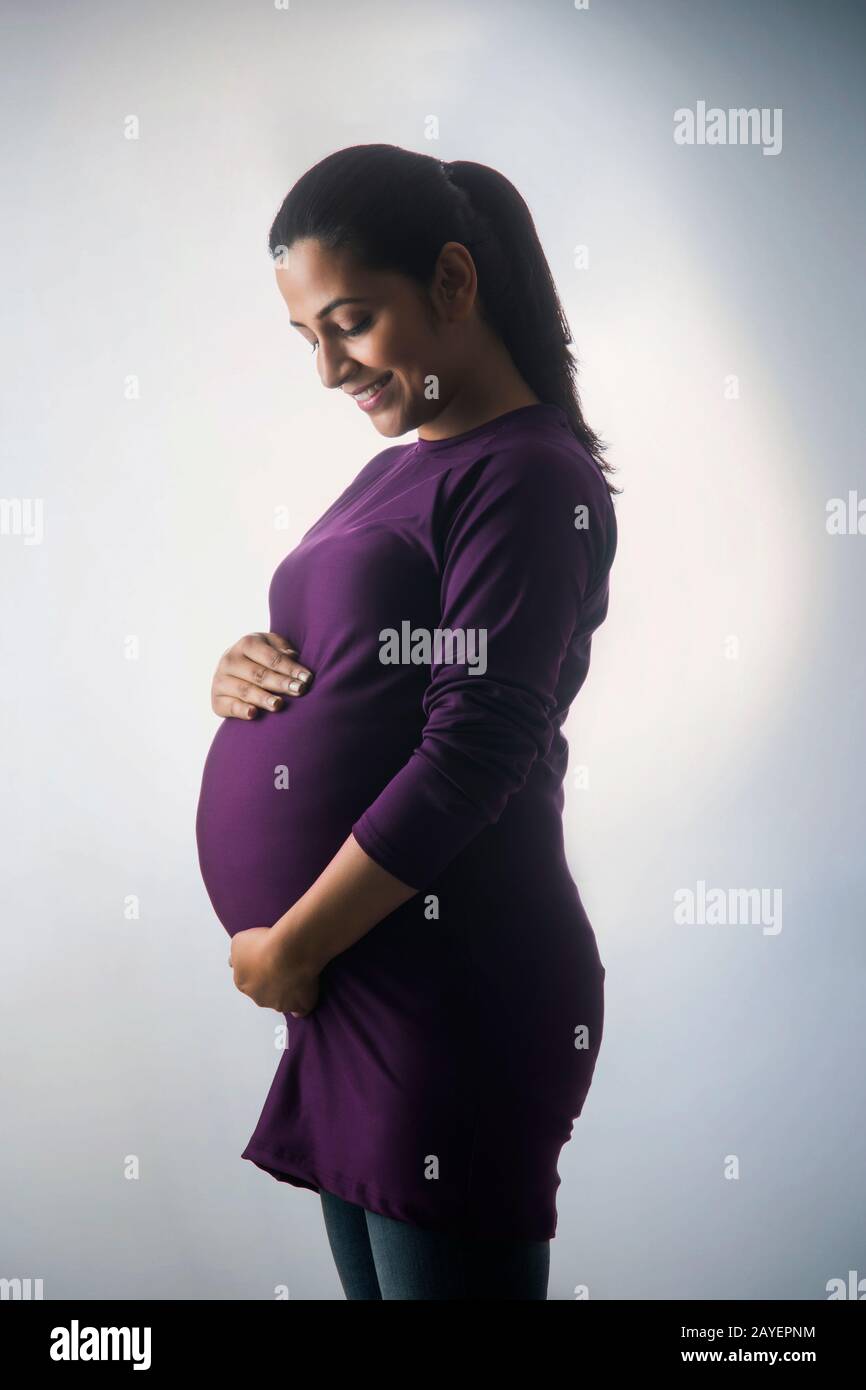 Pregnant woman smiling at her baby bump. Stock Photo
