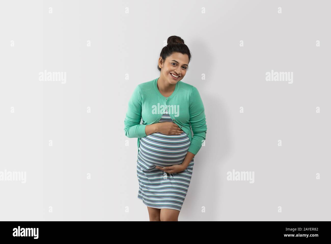 Cheerful pregnant woman holding her belly bump Stock Photo - Alamy