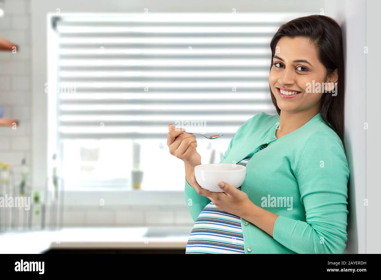 Pregnant woman eating a bowl of cereal in the kitchen Stock Photo Alamy