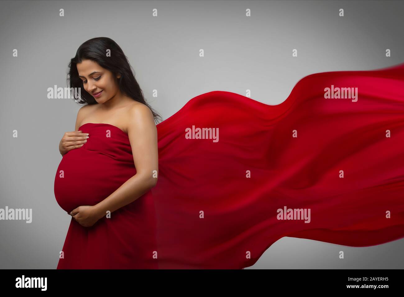 Pregnant woman smiling at her belly bump Stock Photo - Alamy