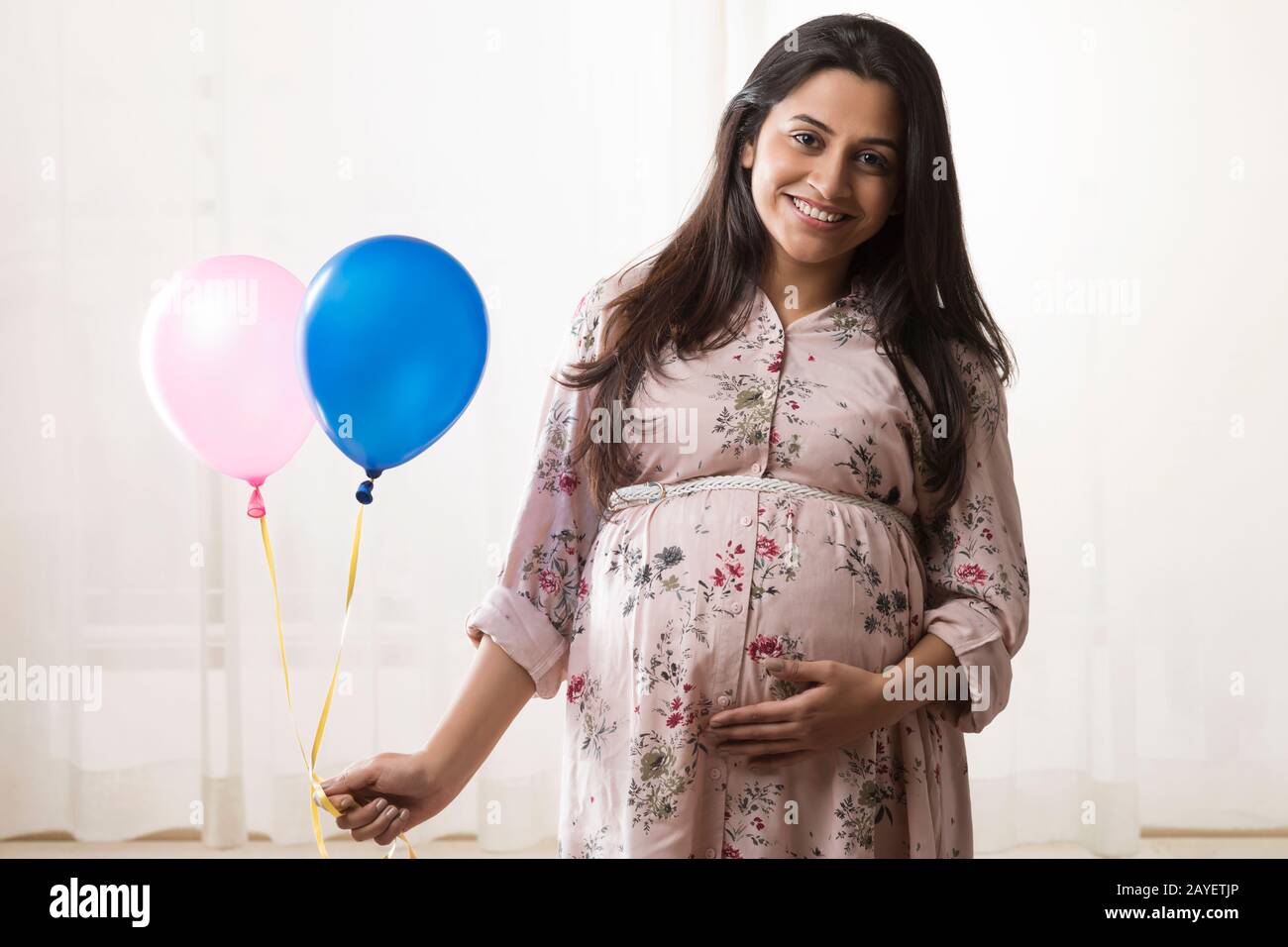 Pregnant woman holding helium balloons in hand. Stock Photo