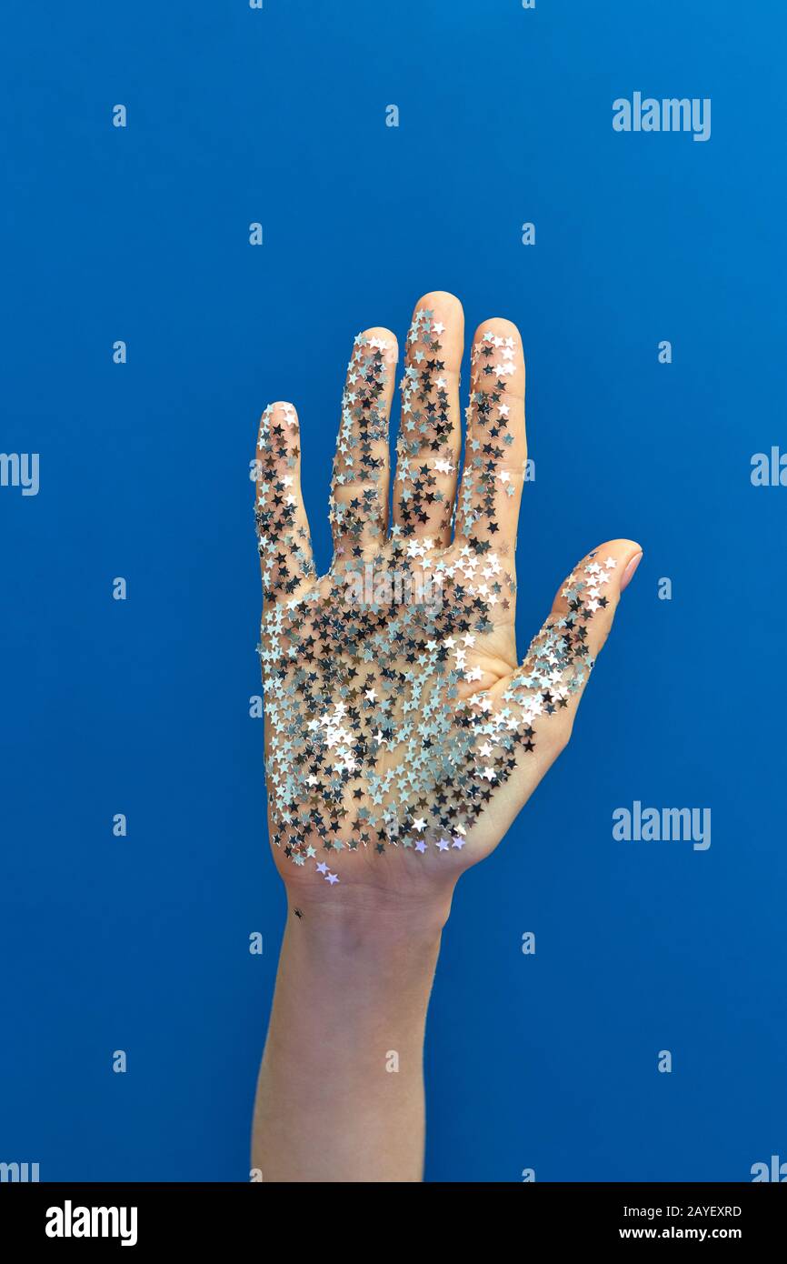 Girl's hand with glitter silver small stars on a blue background Stock ...