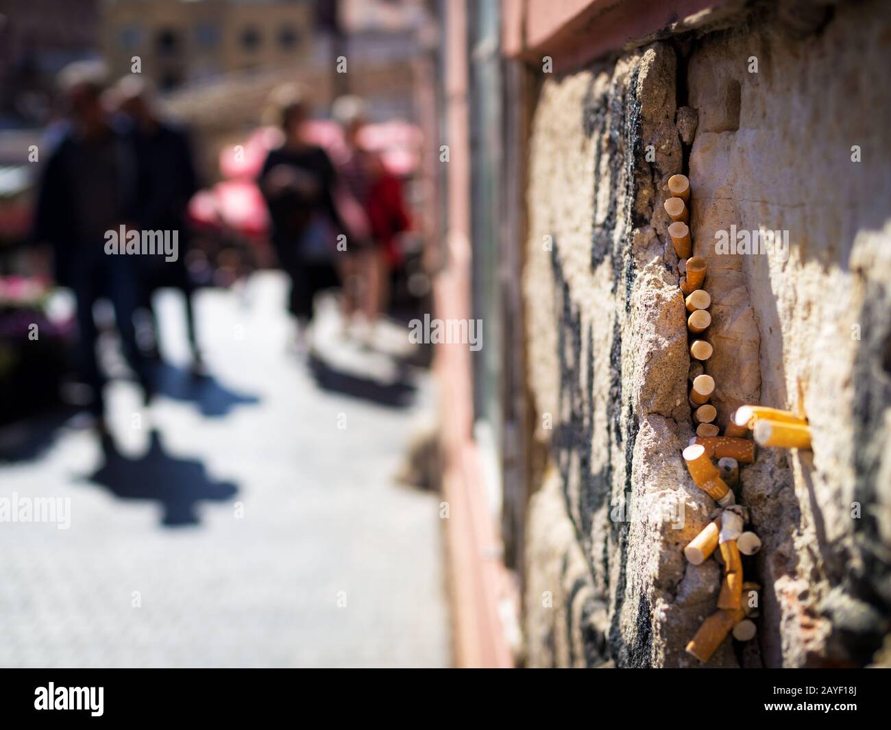 Cigarette ends stick to a gap in a wall on a market Stock Photo