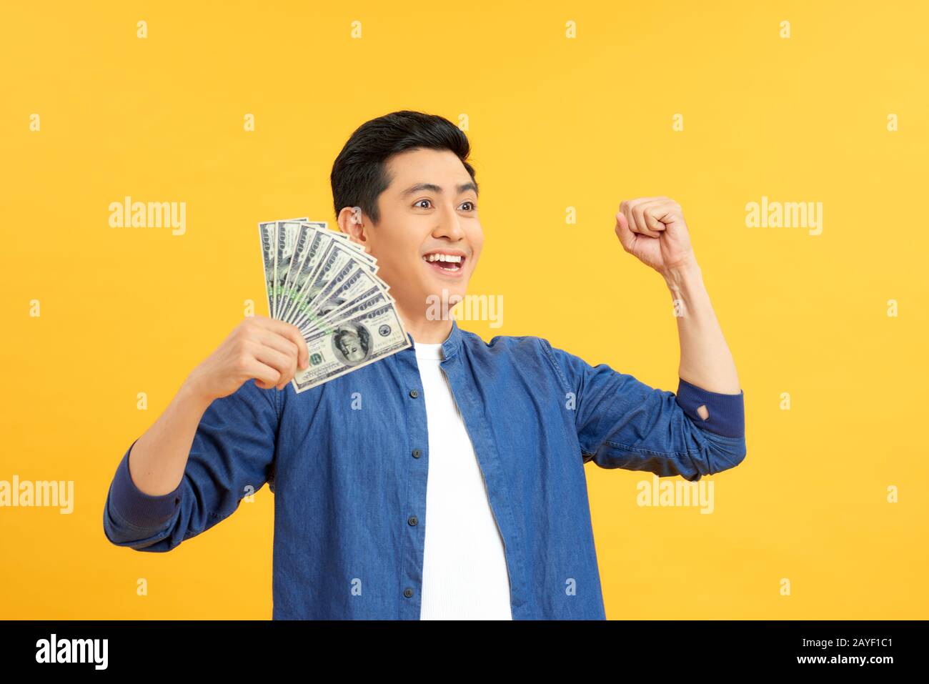 Closeup portrait, happy, excited successful senior lucky elderly man holding money dollar bills in hand isolated yellow background. Positive emotion f Stock Photo
