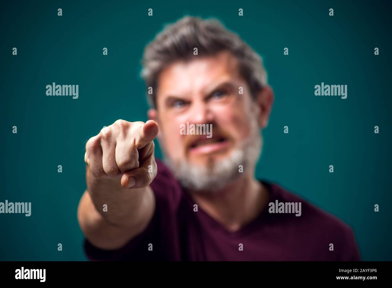 A portrait of angry bearded man in red t-shirt pointing finger at camera. People and emotions concept Stock Photo