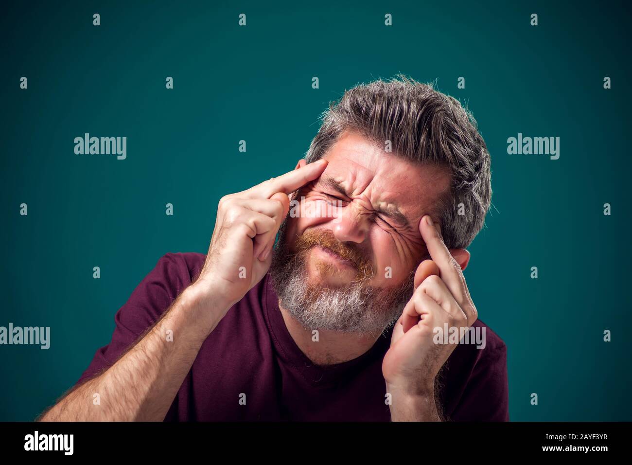 A portrait of bearded man in red t-shirt thinking hard or have headache. People, emotions and health concept Stock Photo