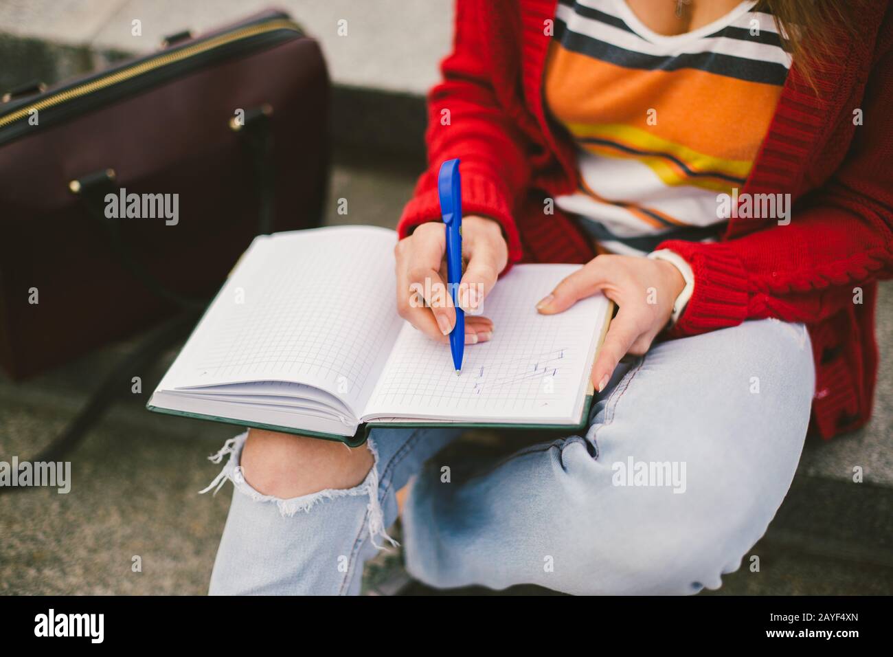 beautiful girl sitting on the street with a notebook and pen in hand ...