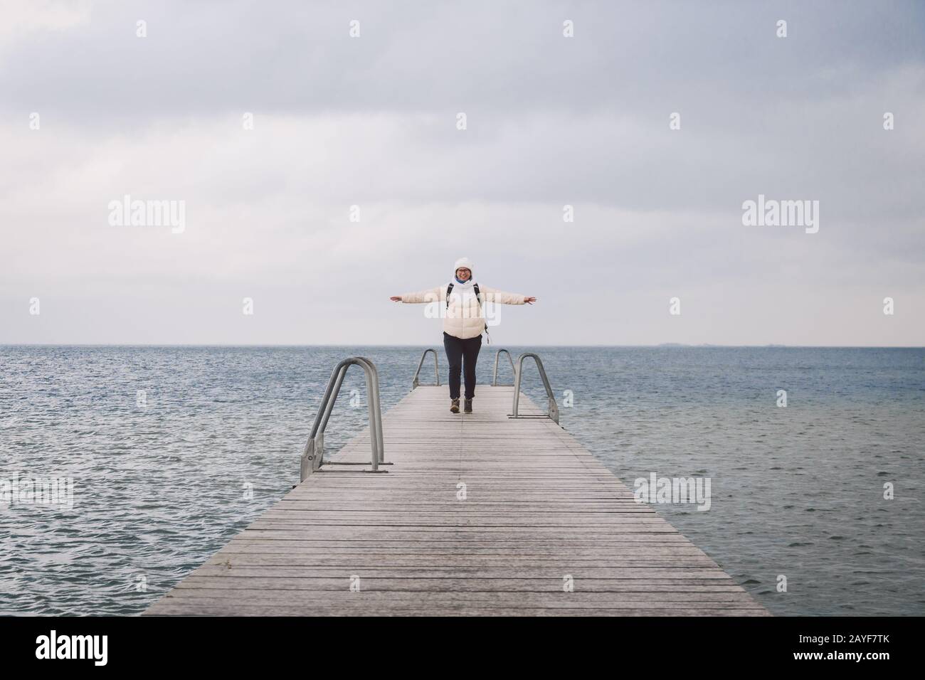 Concept of freedom relaxation. woman relaxing on pier. Woman hiker backpacker with backpack on sea wooden pier goes forward. Emo Stock Photo