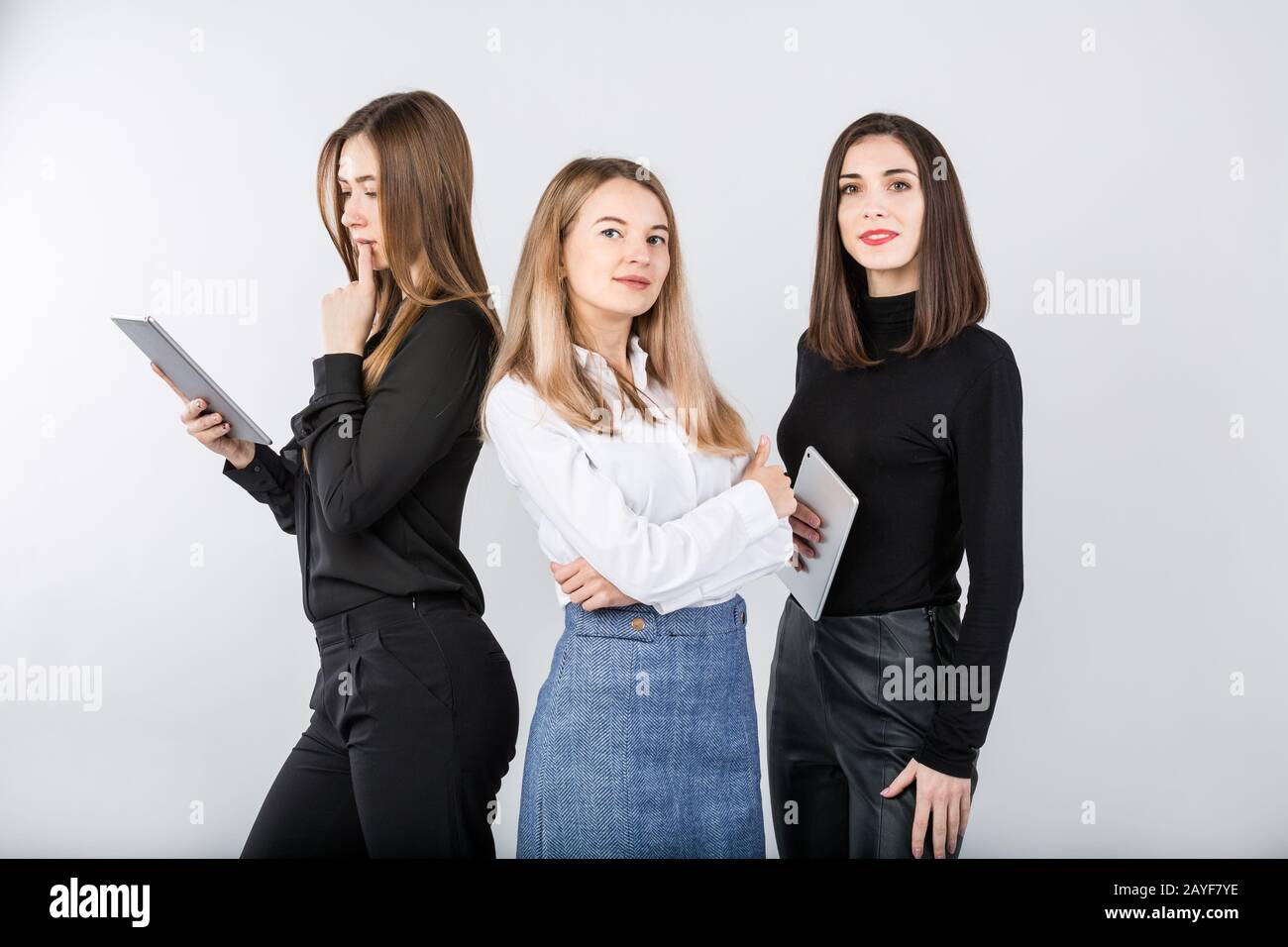 Three smiling business women standing in a row isolated on white ...