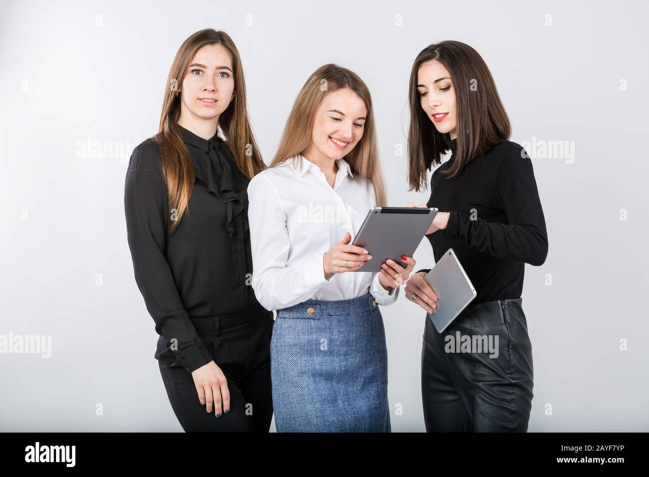 Three smiling business women standing in a row isolated on white ...