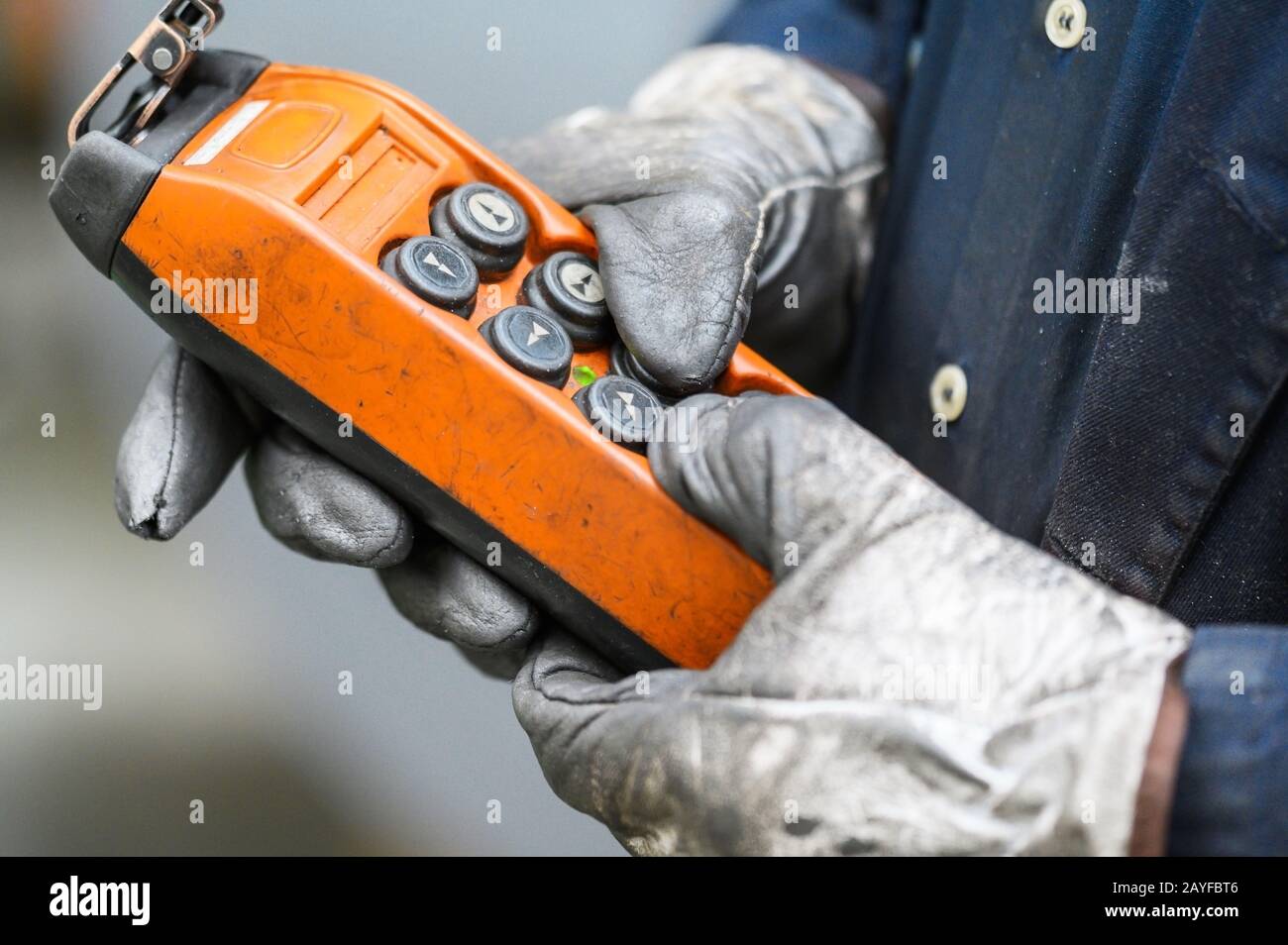 Male hand push remote control switch for overhead crane in the factory, close-up. Electrical control panel of the crane and other lifting equipment in laborer hand . Stock Photo