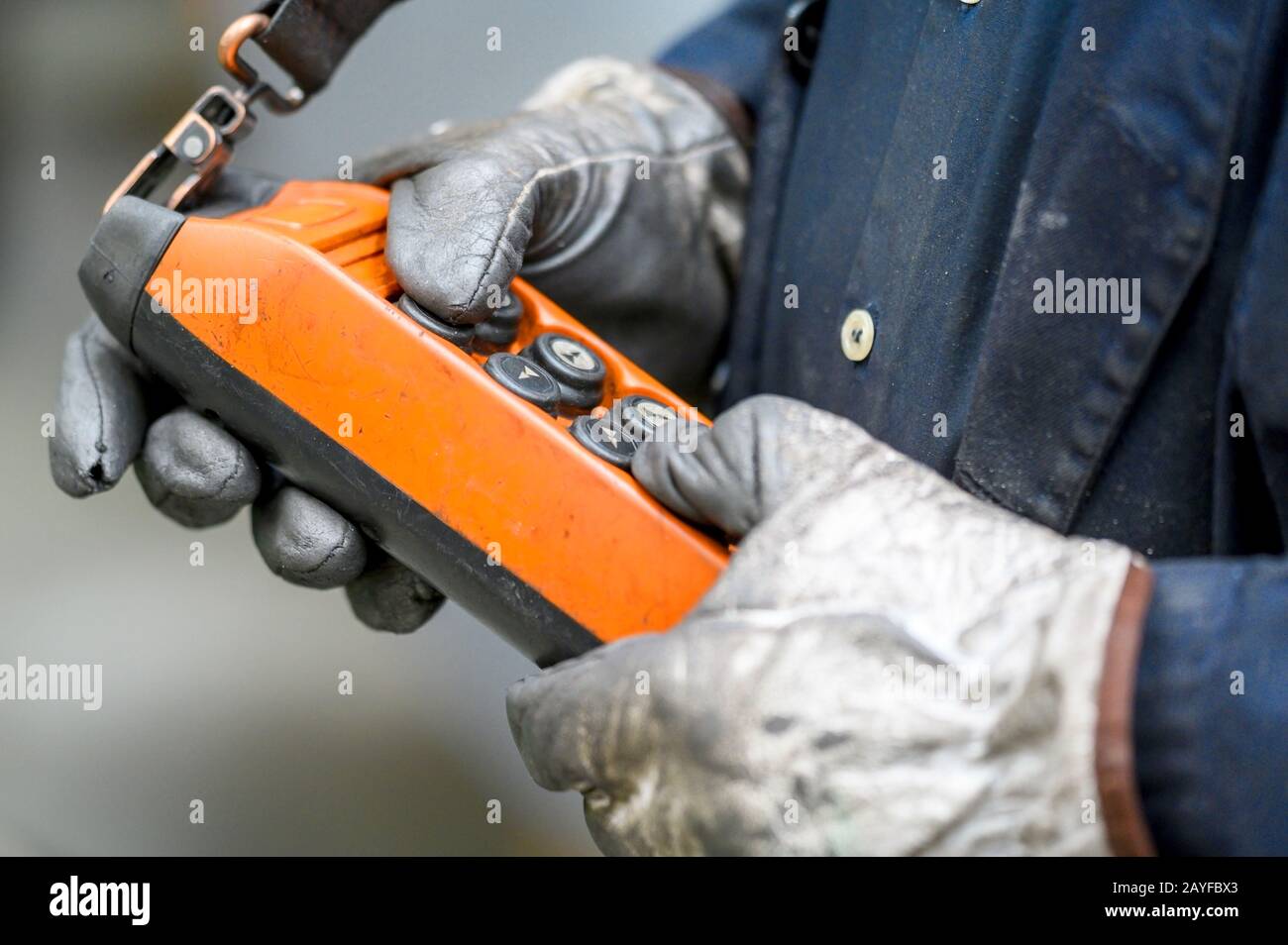 Male hand push remote control switch for overhead crane in the factory, close-up. Electrical control panel of the crane and other lifting equipment in laborer hand . Stock Photo