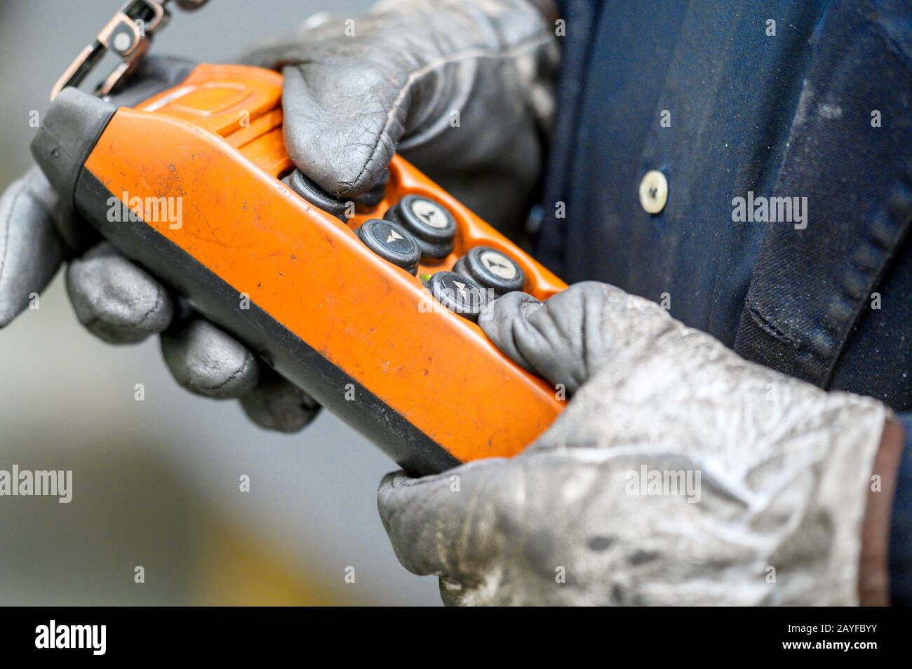 Male hand push remote control switch for overhead crane in the factory, close-up. Electrical control panel of the crane and other lifting equipment in laborer hand . Stock Photo