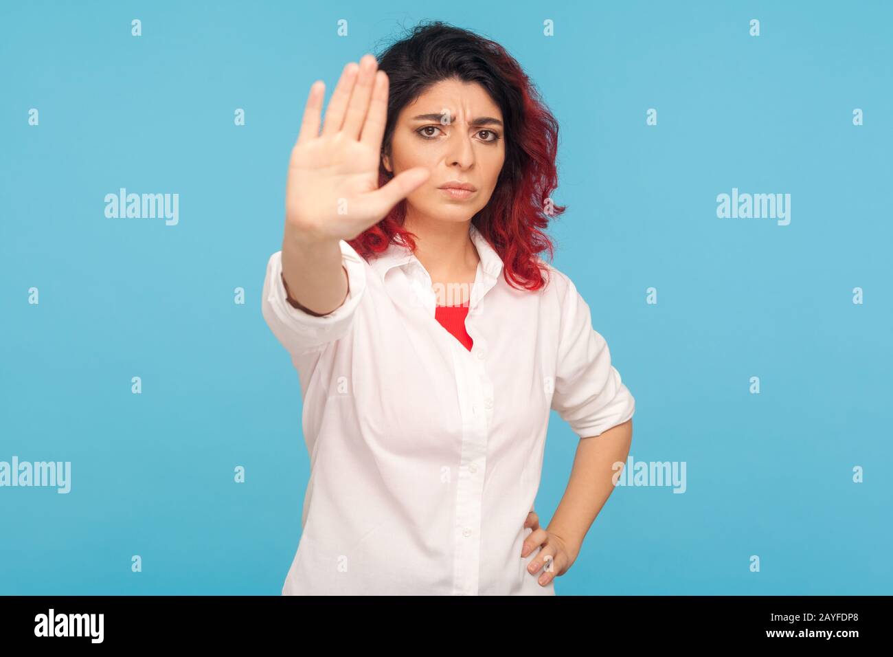 Prohibition concept. Worried woman with fancy red hair showing stop
