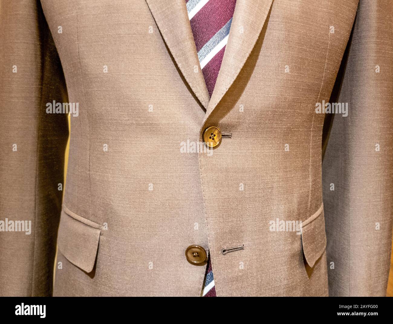 Beige mens suit with red striped tie close up, one button undone Stock Photo