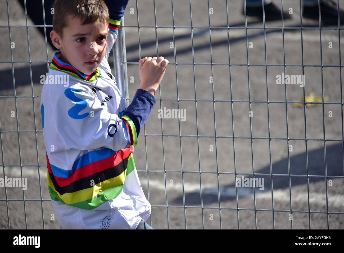 Young cycling fan wearing Alexandre Valverde's rainbow jersey waits for his hero Stock Photo
