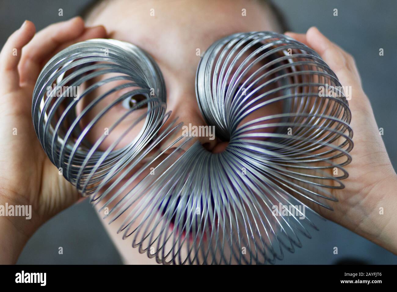 A boy looks through a slinky toy. Stock Photo