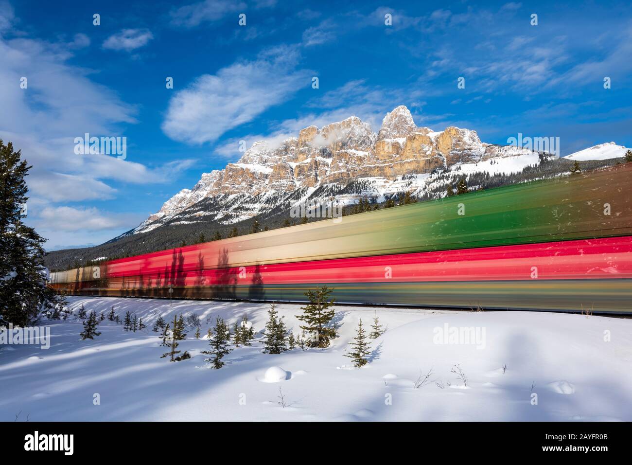 A long exposure of train passing Castle Mountain near Banff, Alberta, Canada Stock Photo