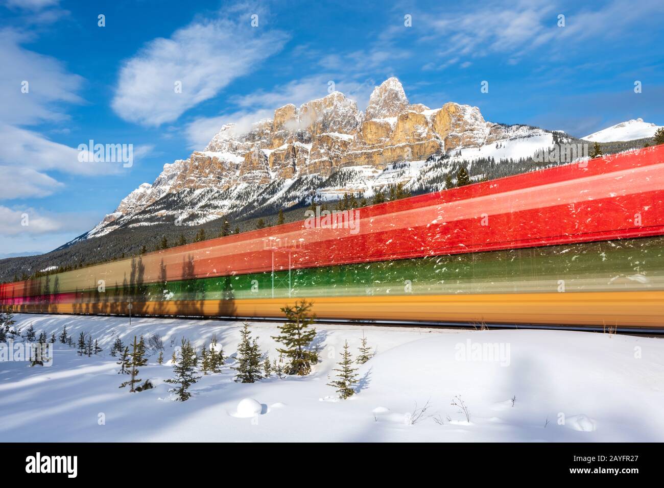 Long exposure of train passing Castle Mountain near Banff, Alberta, Canada Stock Photo