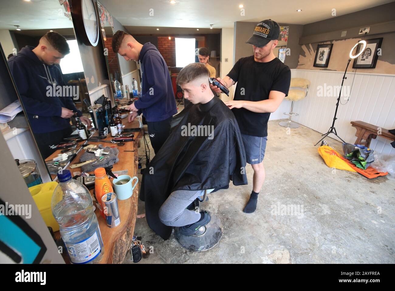 Jack Sutcliffe having a haircut by Carl Faulds in Faulds Barbers in Mytholmroyd in the Upper Calder Valley in West Yorkshire. The laminate floor has been removed after flooding last week as the village braces itself for a second weekend of weather disruption as Storm Dennis sweeps in. Stock Photo