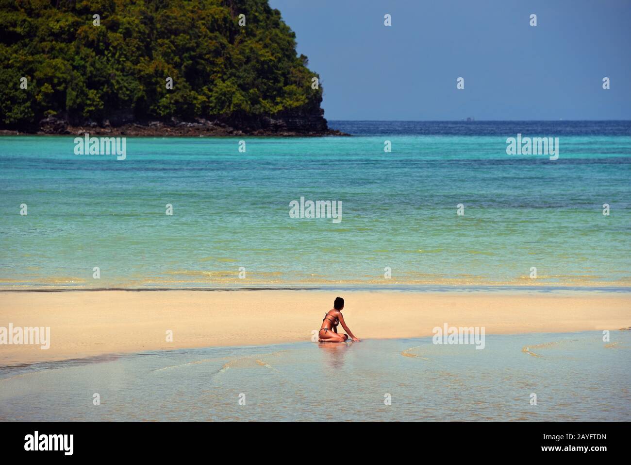 woman in bikini sitting on sandy beach, Thailand, Koh Phi Phi Stock Photo