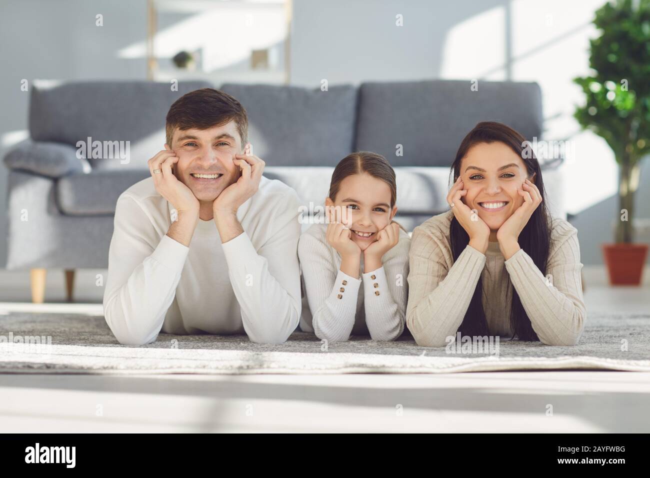Happy smiling family hugging while lying on the floor in the room at home. C Stock Photo