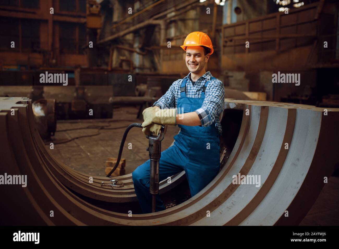 Worker removes scale from metal workpieces Stock Photo